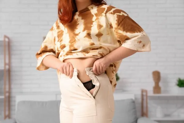 Image of woman trying to do her trousers up after pregnancy weight gain Rochford